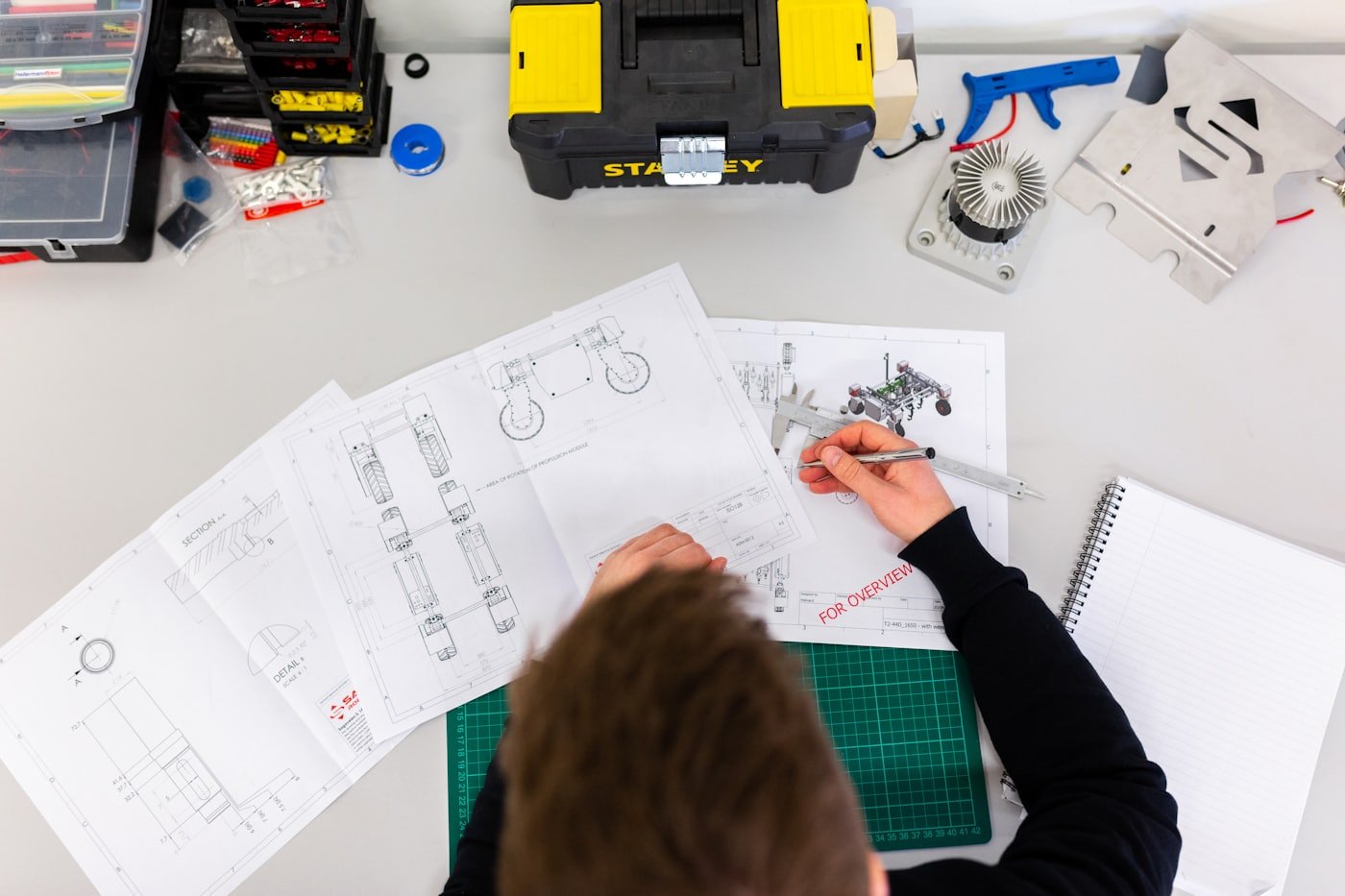 Desenhos técnicos e instrumento de medição sobre a bancada