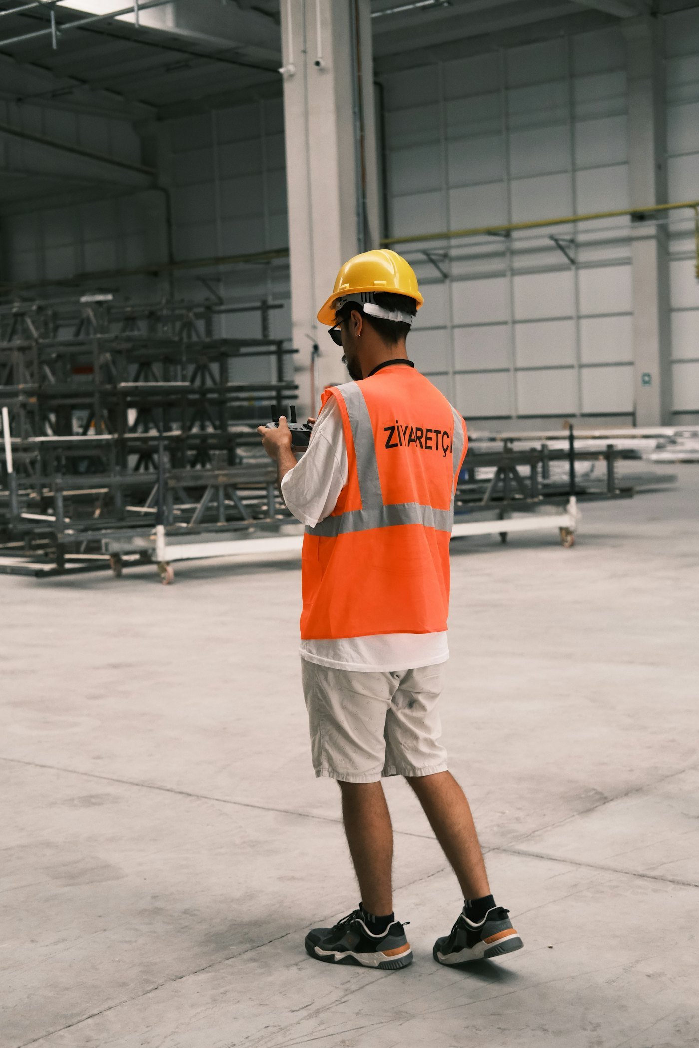 Profissional com capacete e colete refletivo em galpão industrial