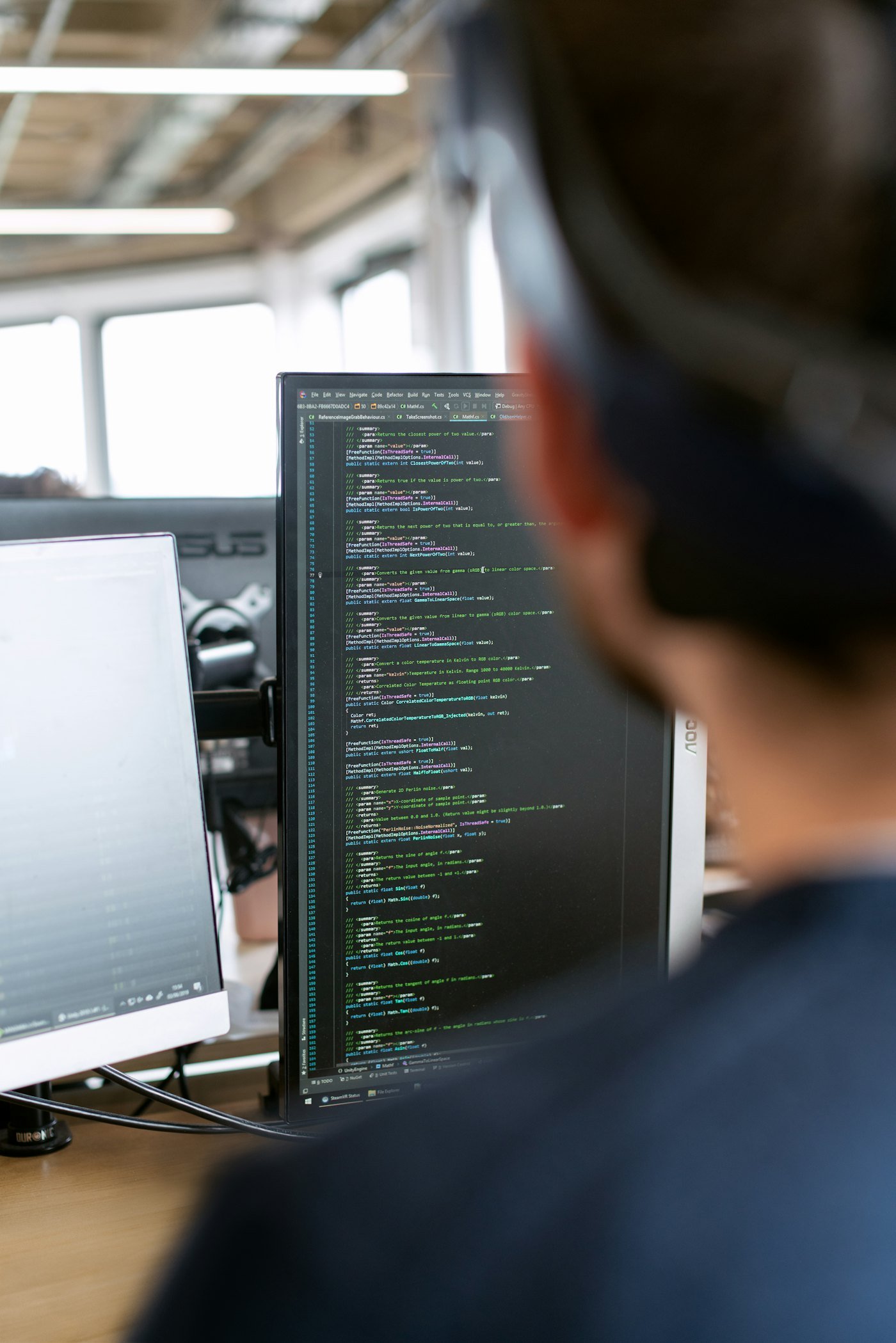 Pessoa programando em frente a um monitor com código